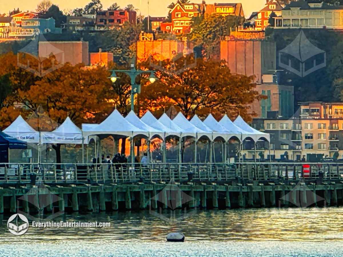Waterfront view of white 10x10 high-peak festival tents installed along Pier 84 at Hudson River Park during sunset by Everything Entertainment.