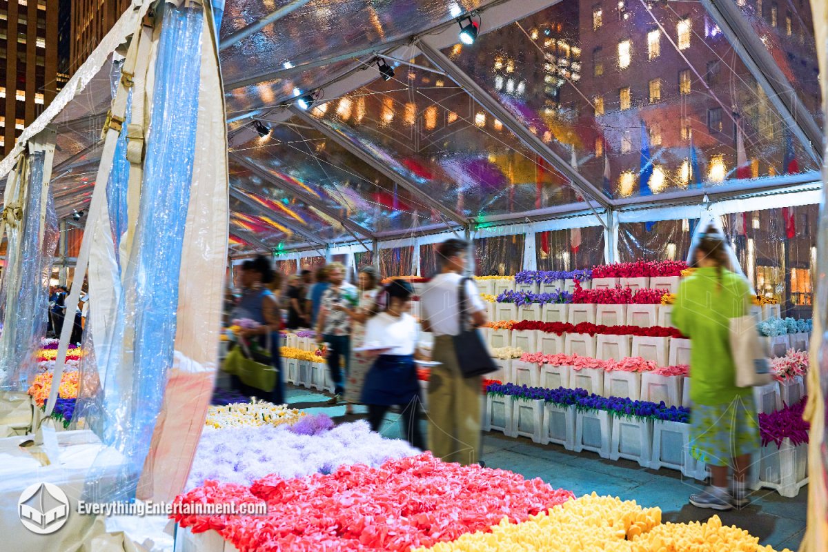 Interior perspective of a 30x130 clear top tent filled with colorful floral displays and visitors during a flower show in Rockefeller Center by Everything Entertainment.