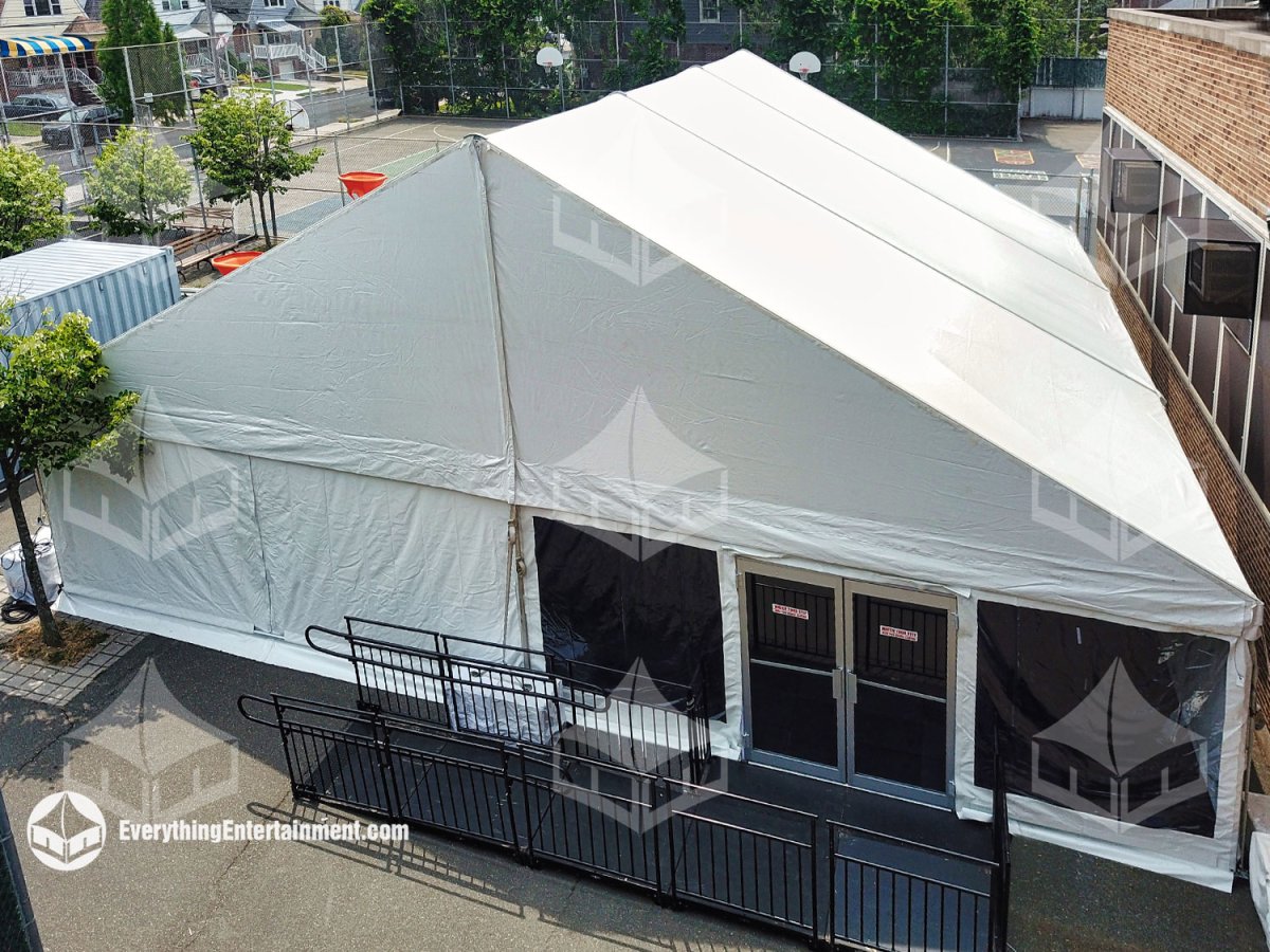 High-angle exterior view of a 40x45 white maxi-frame tent with a custom leveled subfloor, double commercial doors, ADA-compliant ramp, and air conditioning installed by Everything Entertainment in the Rockaways, Queens.