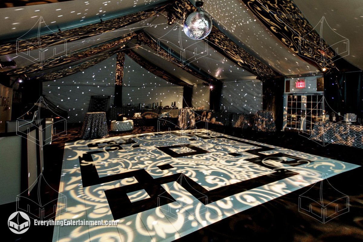 Interior view of a Sweet Sixteen tent with a bespoke black and white dance floor, mirror ball, black ceiling drapery, and gobo light projections by Everything Entertainment.