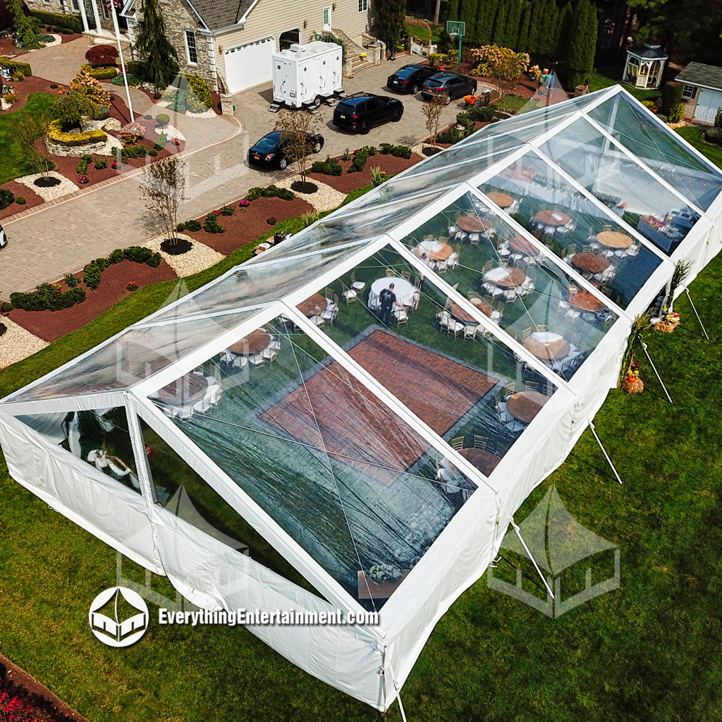 Aerial view of a large clear top wedding tent in backyard.