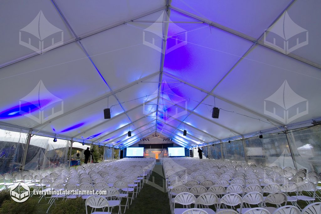 Interior view of a 50x190 corporate presentation tent with seating for 1,000 guests, carpeted subfloor, LED lighting, and rigged AV equipment by Everything Entertainment.