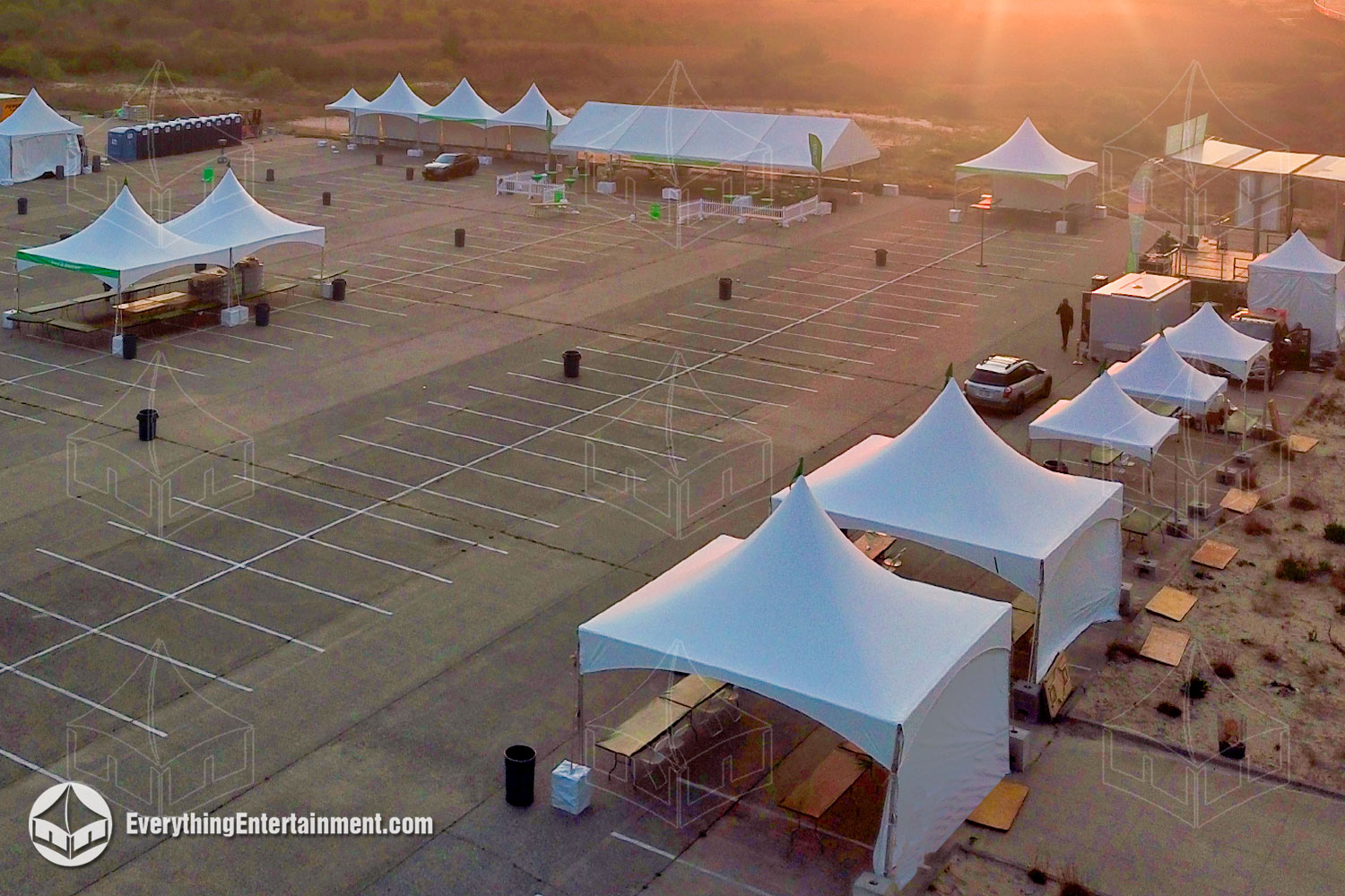 Multiple High Peak Frame Tents setup for awareness walk on asphalt parking lot.