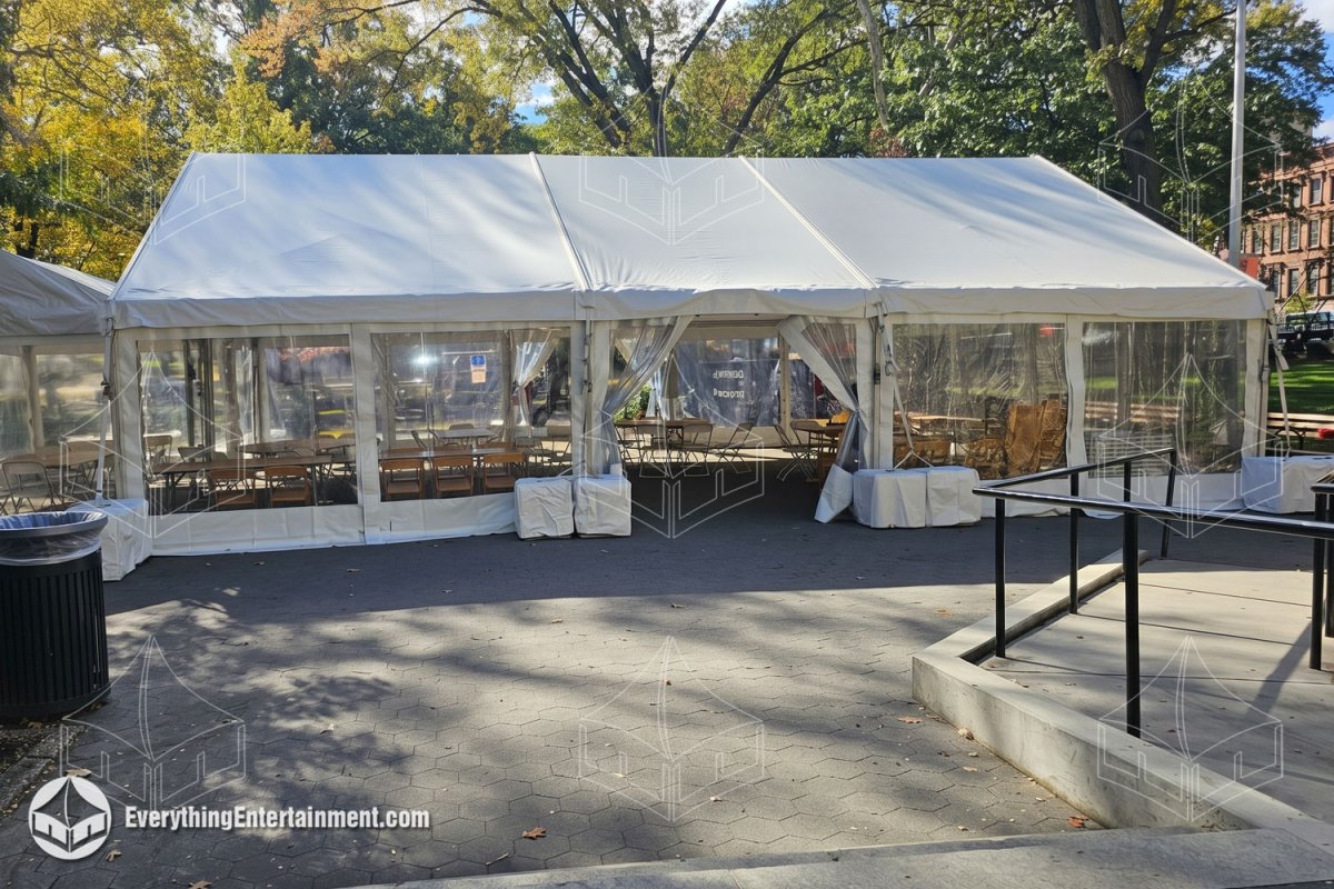 Exterior of a 30x40 frame tent with clear sidewalls, tables, and chairs in a Bronx park by Everything Entertainment