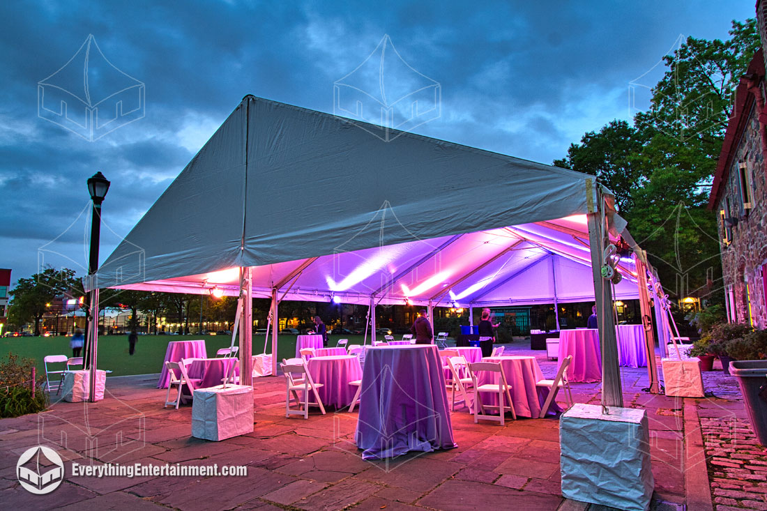 A large sailcloth tent for a backyard wedding with guests seated underneath.