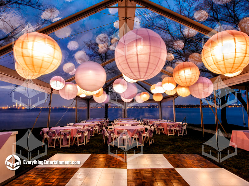 30x60 clear top frame tent rental with paper lanterns with a medium blue evening sky.