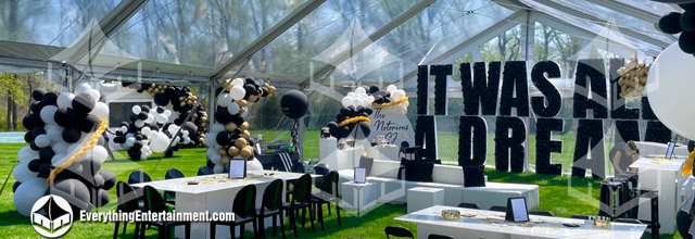 Clear top tent in a backyard with black, white, and gold decor.