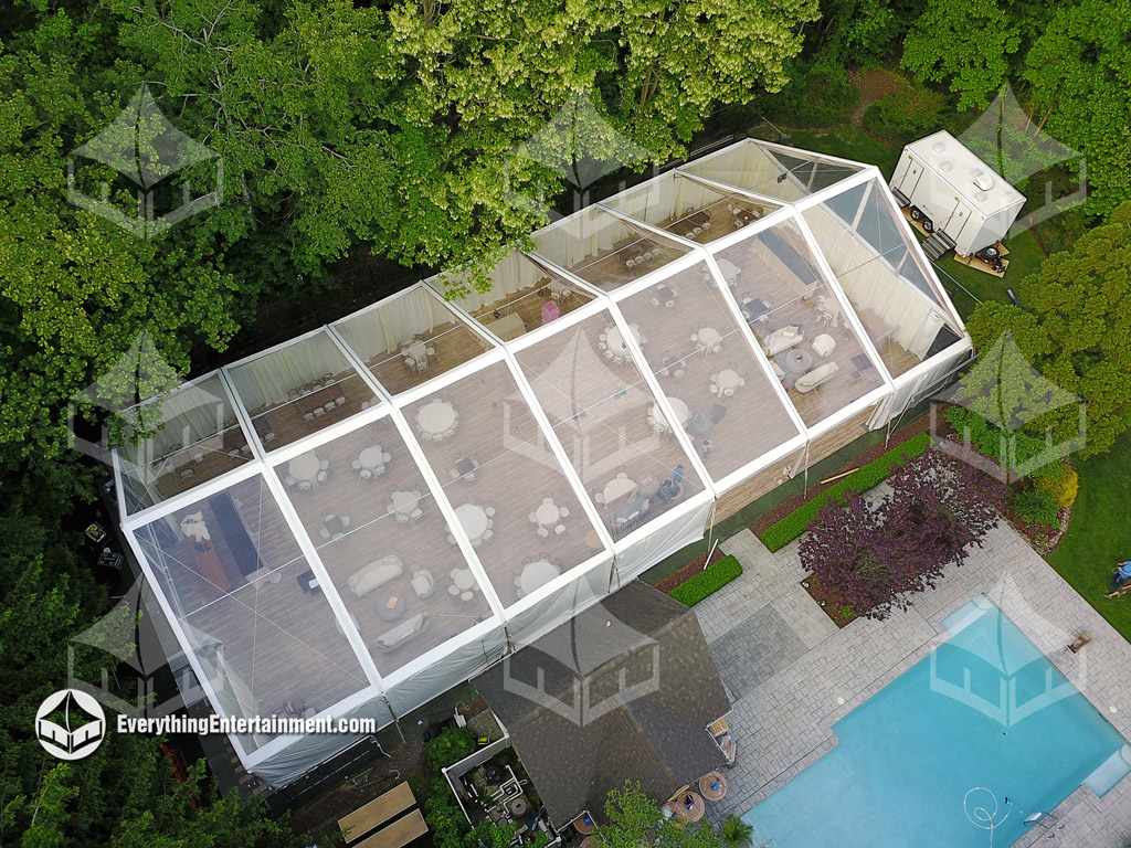 Aerial view of a clear top wedding tent with a pool in the foreground.