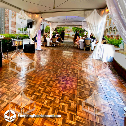 wood style dance floor rental setup under white party tents