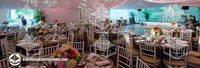 Interior of a wedding tent with fabric drape and tables with beautiful place settings.