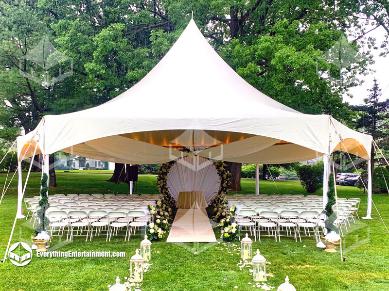 High peak frame tent with chairs for wedding ceremony set up inside.