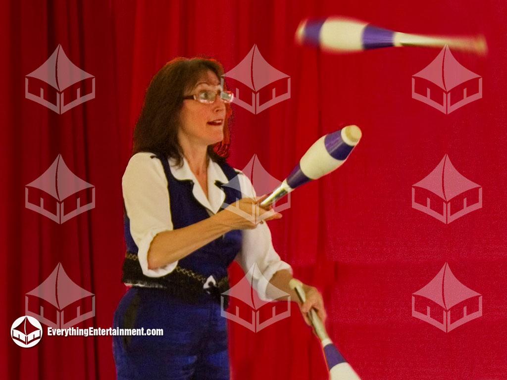 performer juggling pins in front of red backdrop