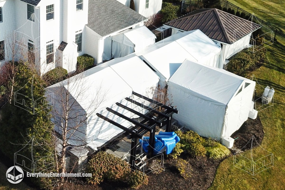 High-angle aerial view of multiple white frame tents custom-fitted around a home's patio and pergola in Alpine NJ by Everything Entertainment.