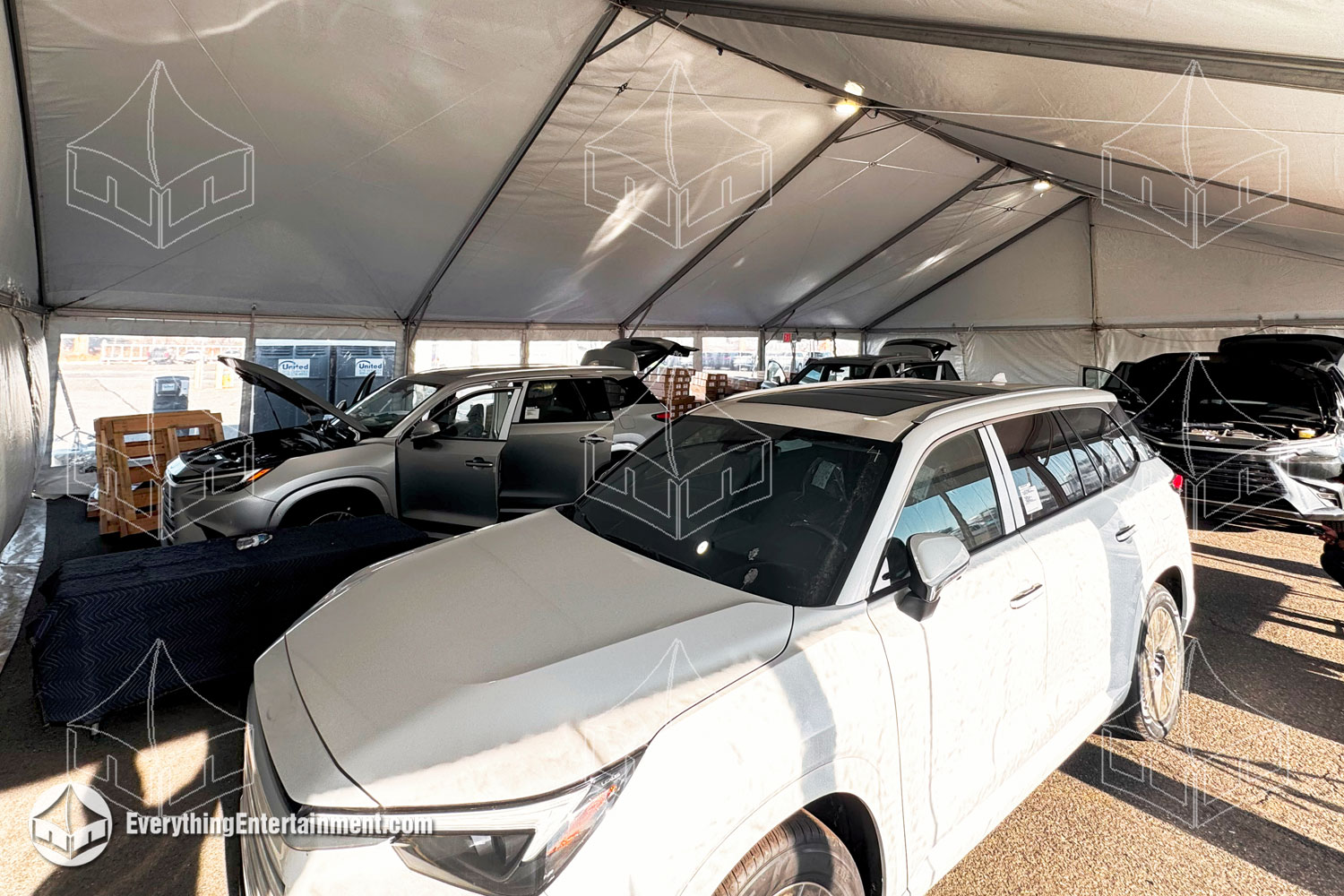 Temporary vehicle repair tent: a large tent sheltering a vehicle repair area, equipped with tools and machinery for on-site service.