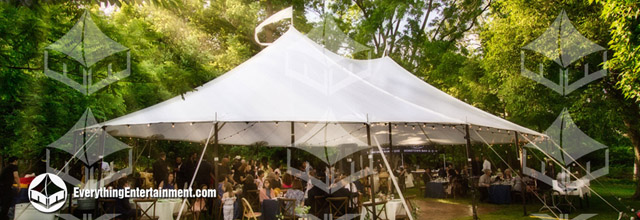 A sailcloth tent setup for a backyard wedding surrounded by trees