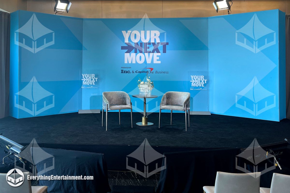 Custom raised stage with black carpeting and an angled blue SEG fabric backdrop build for the Inc. and Capital One Business event by Everything Entertainment in NYC.