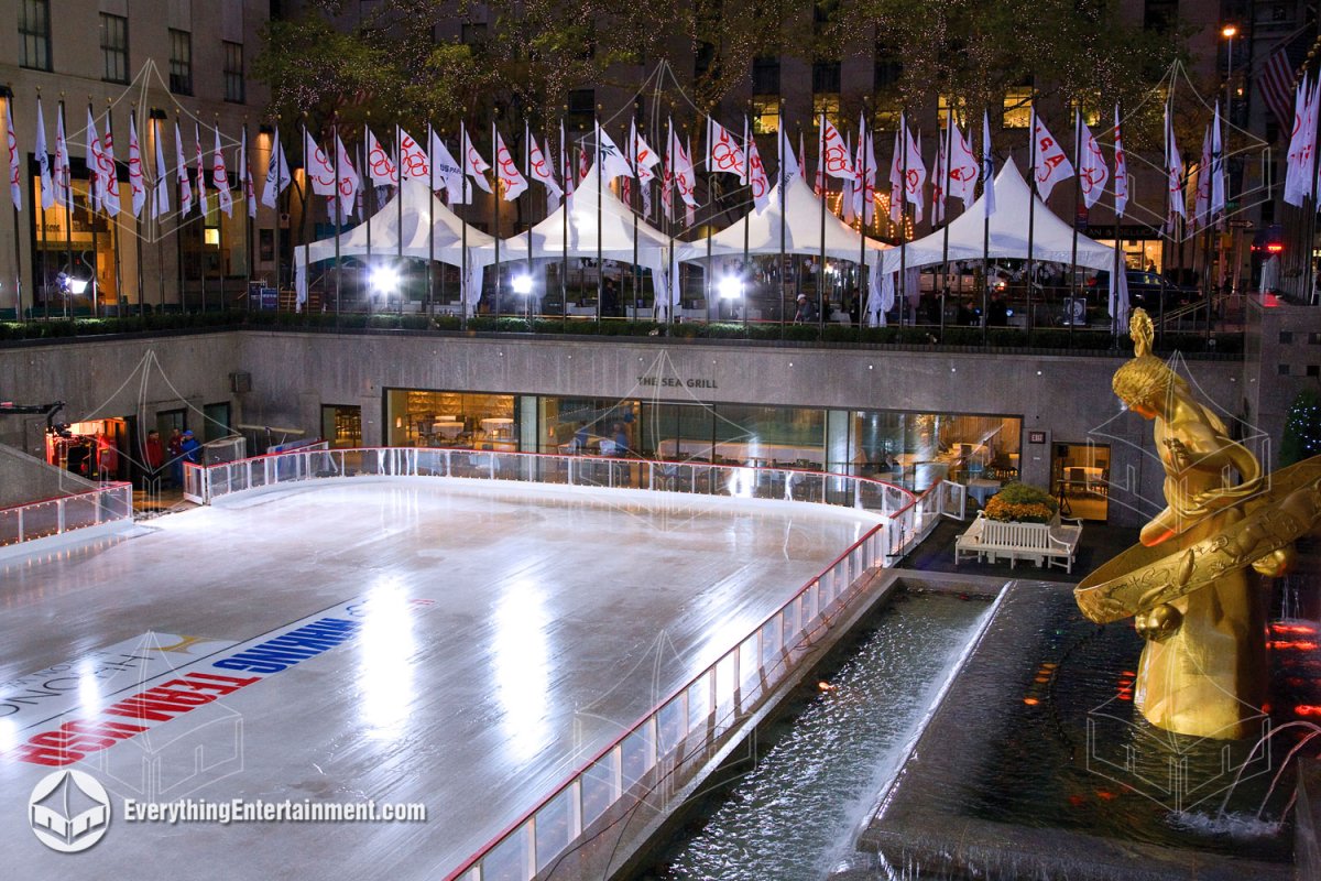 Nighttime view of 15x20 high peak tents with Olympic flags set up above the illuminated ice rink at Rockefeller Center by Everything Entertainment.