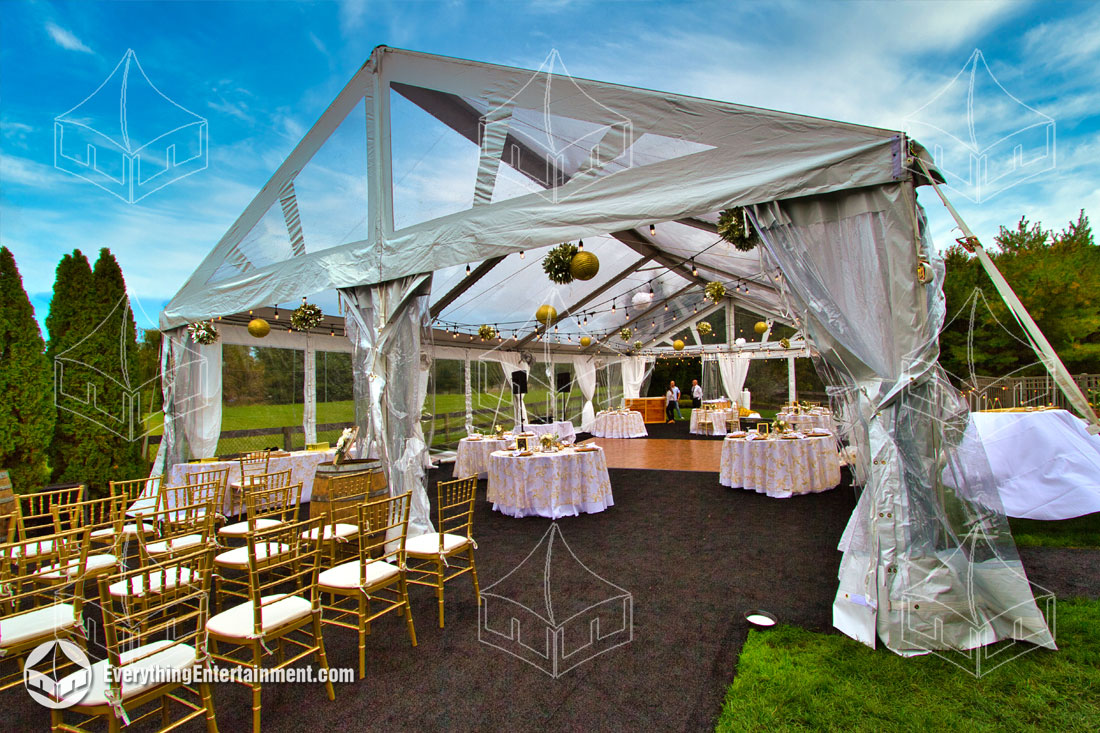 A large sailcloth tent for a backyard wedding with guests seated underneath.