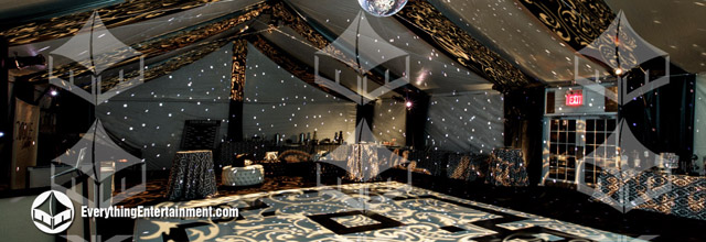 The interior of a large frame tent with a bespoke black and white dance floor and drapery.