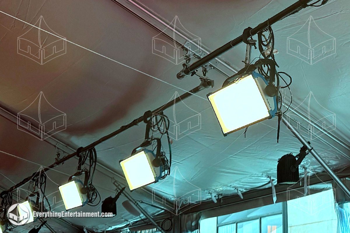 Detail view of broadcast lighting fixtures rigged to the beams of a mono pitch clearspan tent structure using maxi-clamps by Everything Entertainment.