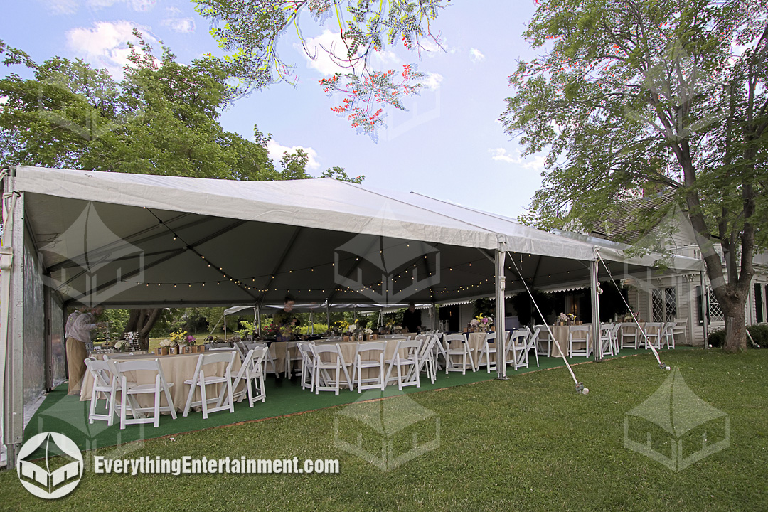 White wedding tent with tables and chairs setup on a grass lawn