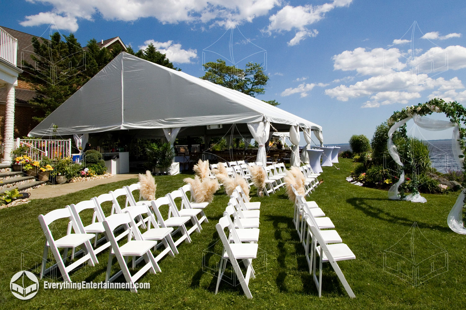 A tent with white garden chairs set for a wedding ceremony, overlooking the ocean in Staten Island, NY